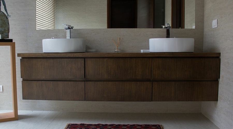 Baño con doble lavamanos sobre mueble de madera oscura