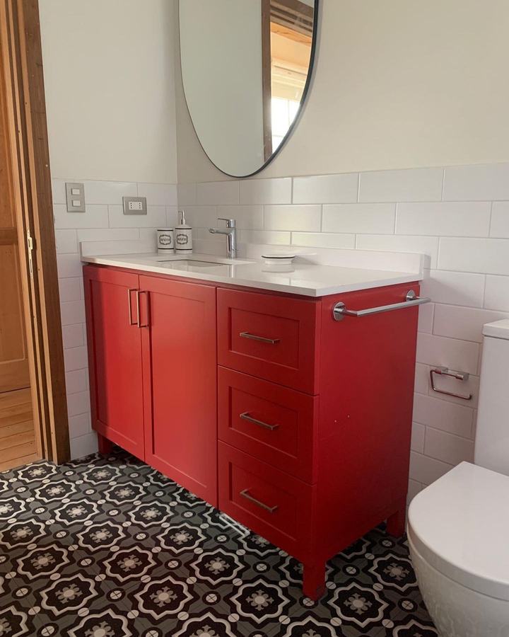 Baño con vanitorio rojo y piso de pastelón