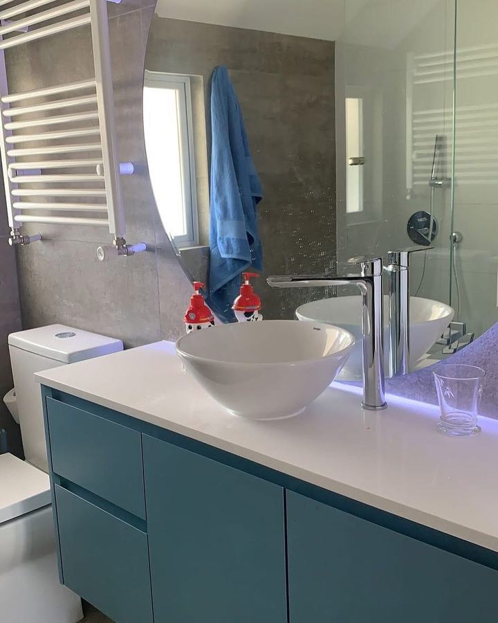 Baño con vanitorio turquesa y lavamanos sobre cubierta