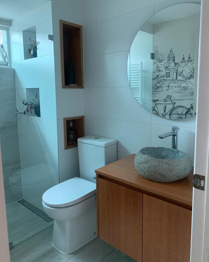 Baño con lavamanos de piedra y espejo redondo