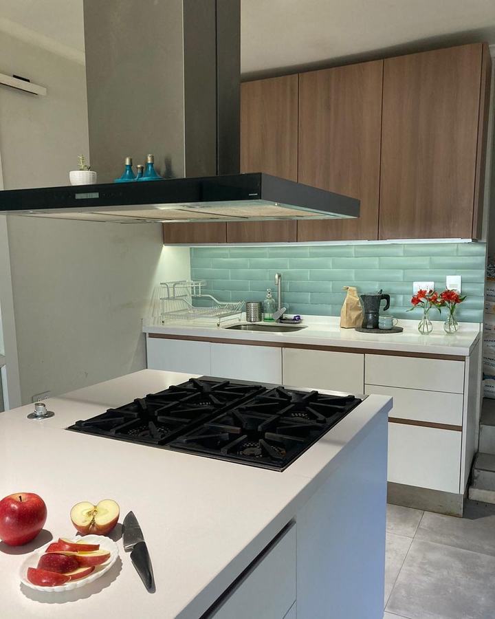 Cocina con isla blanca y revestimiento verde agua