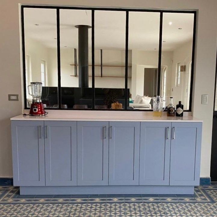 Cocina con isla gris, ventanal de acero y piso hidráulico