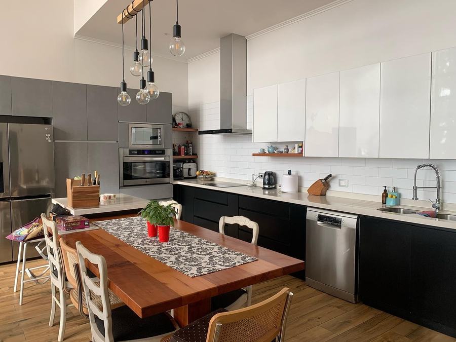 Cocina negra con comedor de madera y lámparas colgantes