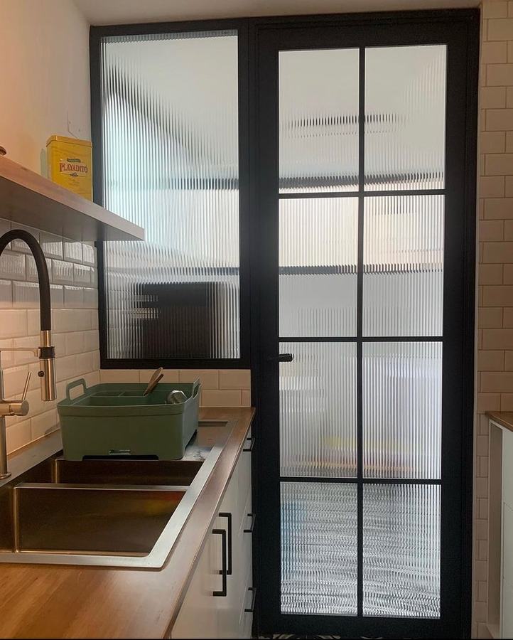 Cocina con puerta corredera de vidrio estriado y marco negro